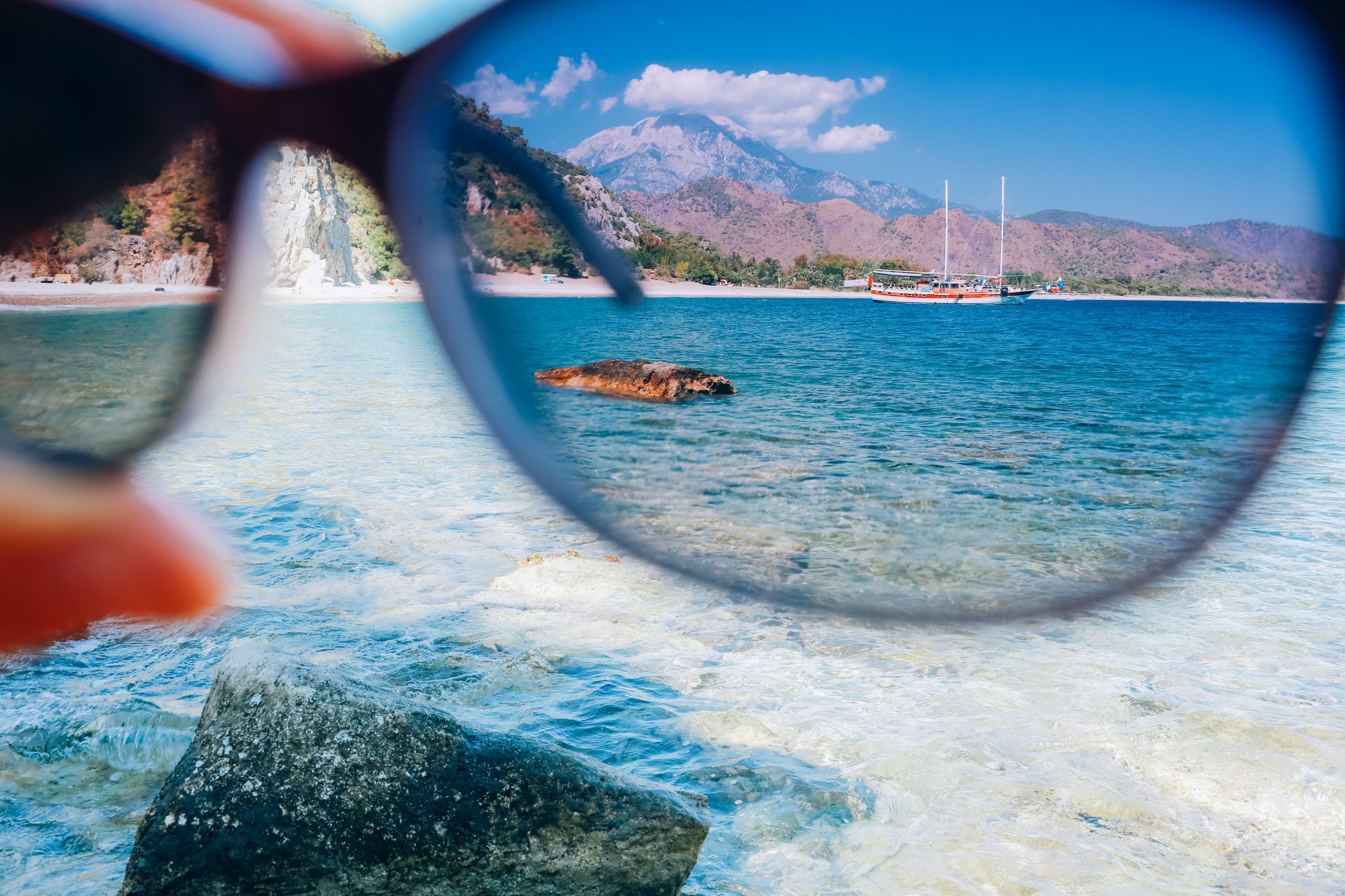 Hand,Holding,Polarization,Sunglasses,Against,Blue,Sky,And,Sea,,Summer