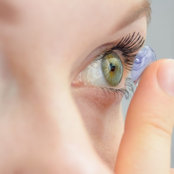 the girl holds on her finger and puts on a soft contact lens for